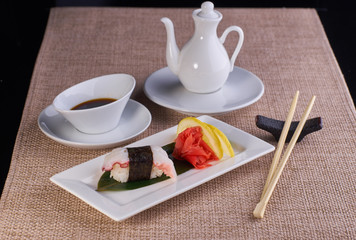 Sushi nigiri with spicy octopus served with chopsticks and soy sauce on table