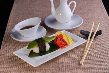 Sushi nigiri with fresh avocado served with chopsticks and soy sauce on table
