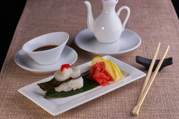 Sushi nigiri with scallop fish served with chopsticks and soy sauce on table
