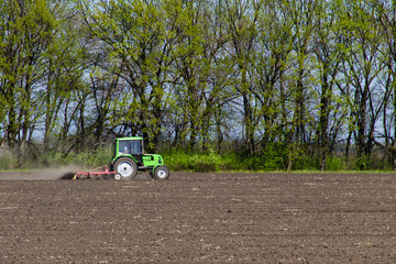 Tractor cultivating field on spring