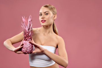 Attractive girl with ananas posing at camera