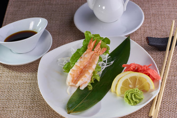 Japanese cuisine. Sashimi with tiger shrimps served with soy sauce and chopsticks on table.