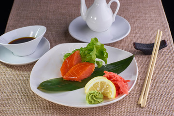 Japanese cuisine. Sashimi with smoked salmon served with soy sauce and chopsticks on table.