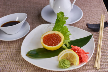 Japanese cuisine. Sashimi with salmon caviar served with soy sauce and chopsticks on table.