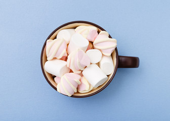 Sweet marshmallow in cup, candy on blue background, top view flat lay. Isolated minimal concept above decoration, view white marshmallow, food background