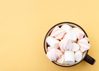 Sweet marshmallow in cup, candy on yellow background, top view flat lay. Isolated minimal concept above decoration, view white marshmallow, food background