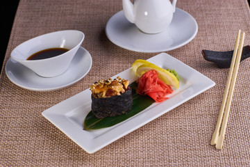 baked sushi with eel fish and mayonnaise served with chopsticks and soy sauce on table