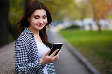 Obraz premium Young pretty stylish smiling woman reading message on smart phon