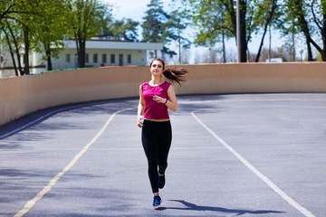 Young pretty fit woman jogging at the athletic field