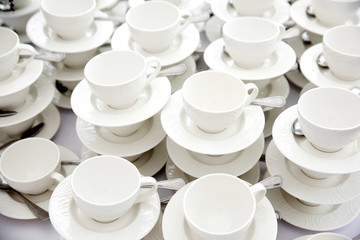 Plenty of white cups on saucers