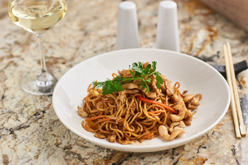 Thin egg noodles with chicken slices served on white plate with white garlic and red spicy sauce