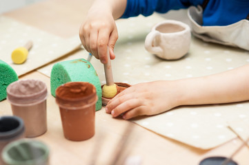 Coloring the ceramic cup. Hands and devices close-up