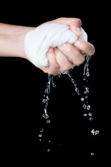 Hand squeeze wet fabric over dark background