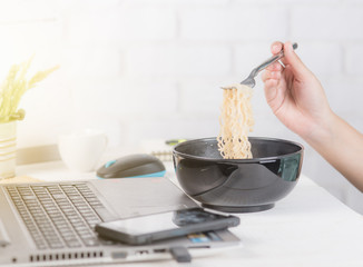 Eating hot Instant noodle at office desk in front of laptop