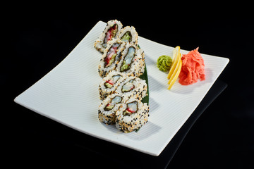 Sushi roll with scallop with vasabi, pickled ginger and lemon slice on white plate on black background