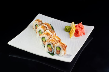 Sushi Roll withsalmon avocado and sesame with vasabi, pickled ginger and lemon slice on white plate on black background