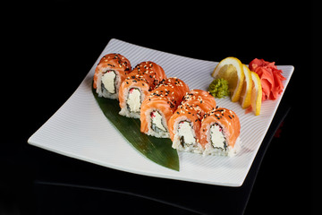 Sushi Roll Philadelphia served with vasabi, pickled ginger and lemon slice on white plate on black background
