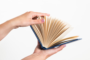 CLose up of female caucasian female woman holding blue opened book isolated on blue background. Horizontal color point of view shot.