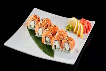 Sushi Roll Philadelphia served with vasabi, pickled ginger and lemon slice on white plate on black background