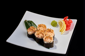 Baked Sushi Roll with crab meat, salmon and avocado served with vasabi, pickled ginger and lemon slice on white plate on black background