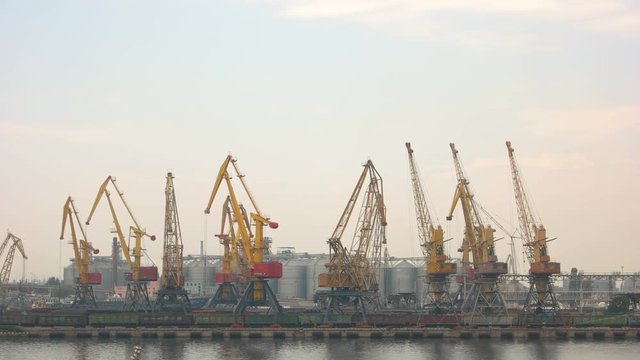 Harbor cranes on sky background. Storage tanks and buildings. Port handling equipment.