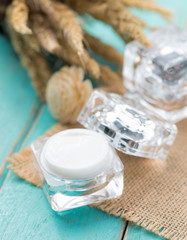 Moisturizing face cream in open glass jar on wood