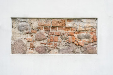 Old stone wall fragment in white plastered wall as background frame
