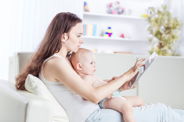 happy mother showing his year-old baby pictures on digital tablet