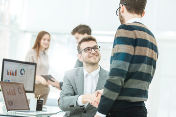 handshake colleagues near the workplace in the modern office.