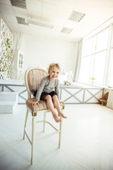 Fototapeta na wymiar portrait of a happy five year old girl sitting on a chair in the spacious living room