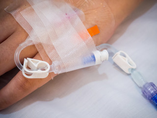 Asian woman patient hand on IV drip with saline solution, fluid replacement therapy
