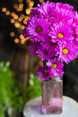 Gorgeously vivid pink flower bouquet in front of twinkly lights.