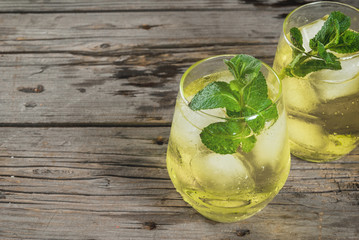 Traditional Spanish alcoholic drink, Rebujito cocktail - white wine, carbonated water (soda), mint, lemon juice. On a rustic wooden table, two glasses. Copy space