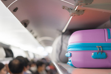 Carry-on luggage on the top shelf  over head on airplane, passenger put bag cabin compartment air craft ,vintage color,copy space