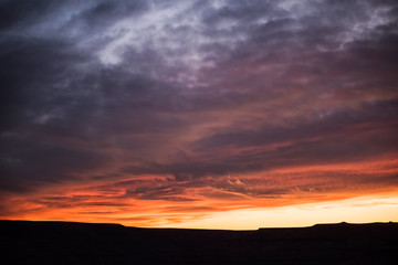 Dramatic colorful red purple and stormy sunset in goosenecks park in Utah with canyons