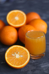 Orange juice in a glass and oranges on a concrete background