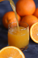 Orange juice in a glass and oranges on a concrete background