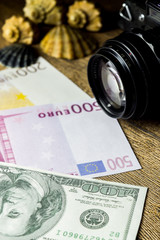money with shells and old fotocamera on the wooden table