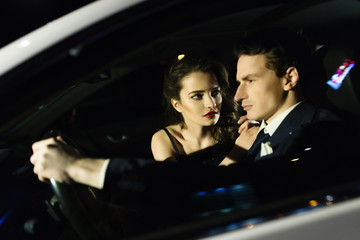 Beautiful boy and girl sitting in the car, the reflection of the street in the glass of the car. Love story