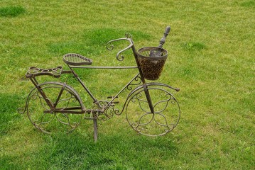 Декоративный металлический велосипед с корзинкой и совком стоящий на газоне