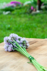 Flower chives tied in a snop on a natural wooden cutting board © Miroslav Beneda