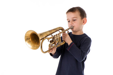 young boy blowing into a trumpet against white background