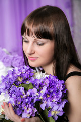 Beautiful young girl with a bouquet of purple flowers