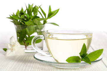 Glass cup of tea with jasmine and mint on the white background