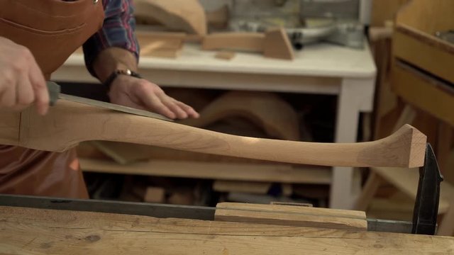 Joiner Polishes Cabrioli Leg in his Workshop/Cabinet maker polishes the cabriolet leg with a file. He works in a small family joiner&rsquo;s shop. Close-up