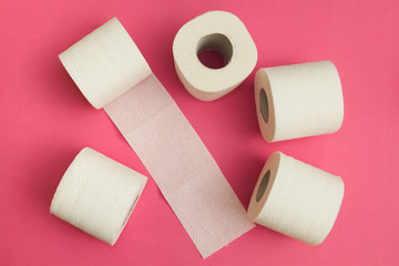 Rolls of white toilet paper on a pink background.