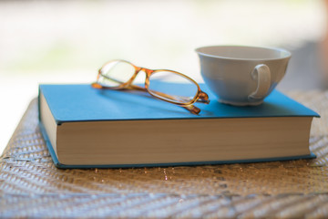Book, cup and eyeglasses on a chair.