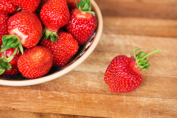 Fresh ripe strawberries in plate on a wooden background