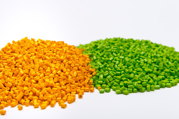 Green and orange plastic pellets on a white background. Polymeric dye for plastics.