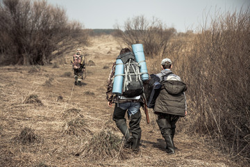 Scène de chasse avec des chasseurs avec des sacs à dos et des munitions de chasse traversant une zone rurale avec des buissons pendant la saison de chasse